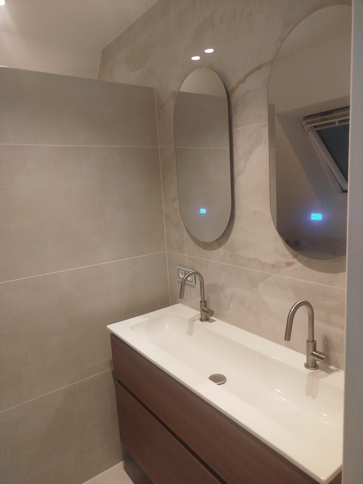 Dubbele wastafel met twee ovale verlichte spiegels en een donker houten kast — Vesta Lux project in Zeeland